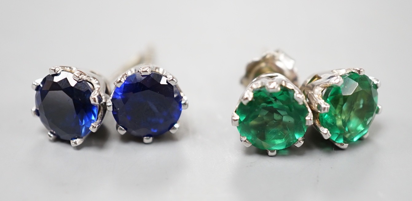 Two pairs of white metal ear studs, one set with green paste, the other with synthetic sapphires, the latter with no butterflies.
